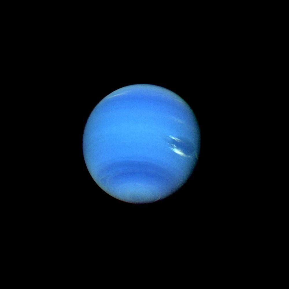 Netuno, um planeta de azul intenso, com nuvens brancas finas